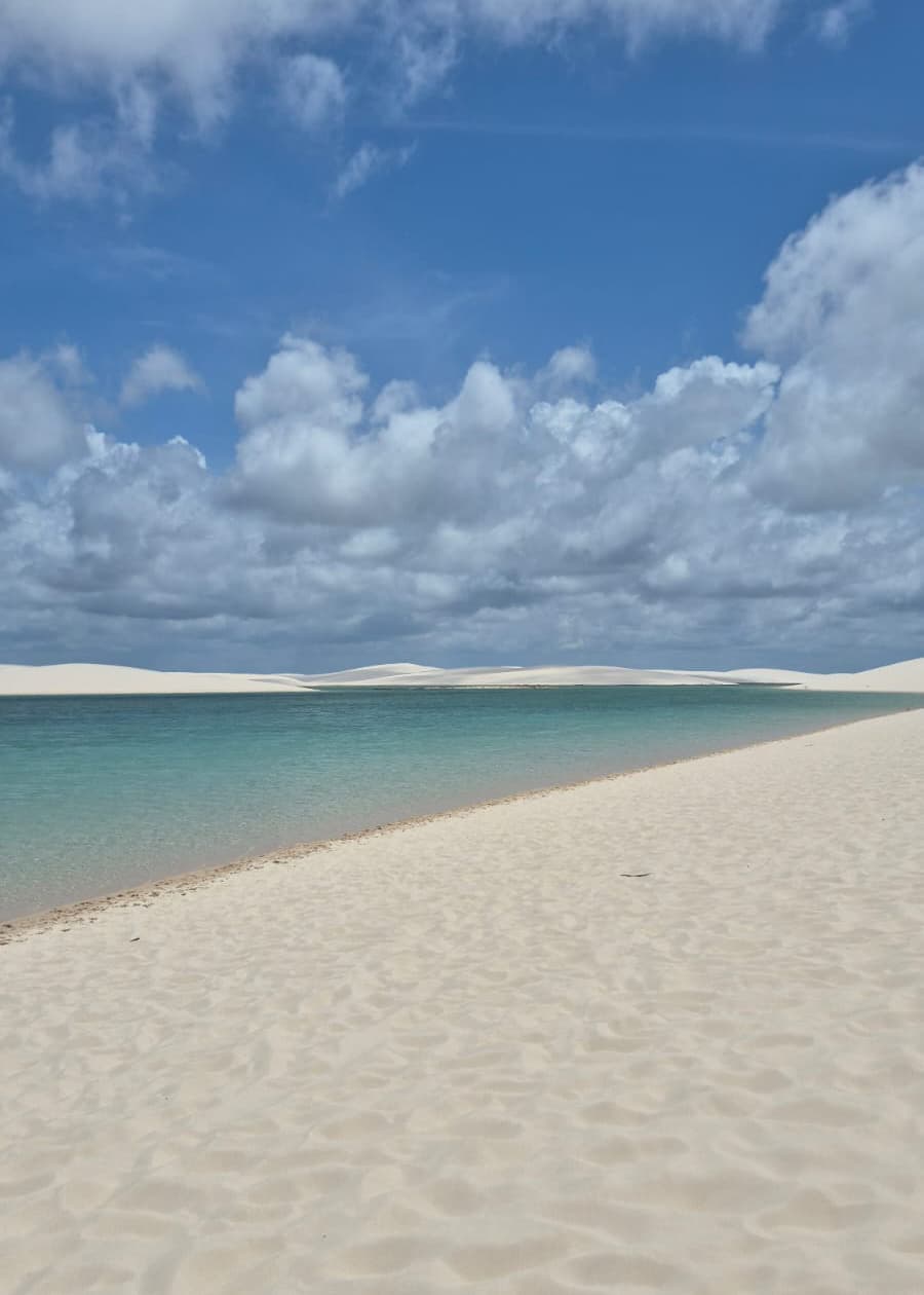 Lagoa turquesa ampla com dunas brancas ao fundo no Circuito Ponta Verde dos Lençóis Maranhenses