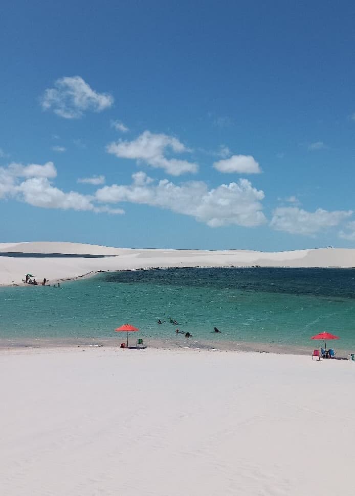 Banhistas na Lagoa da Andorinha entre dunas brancas nos Lençóis Maranhenses