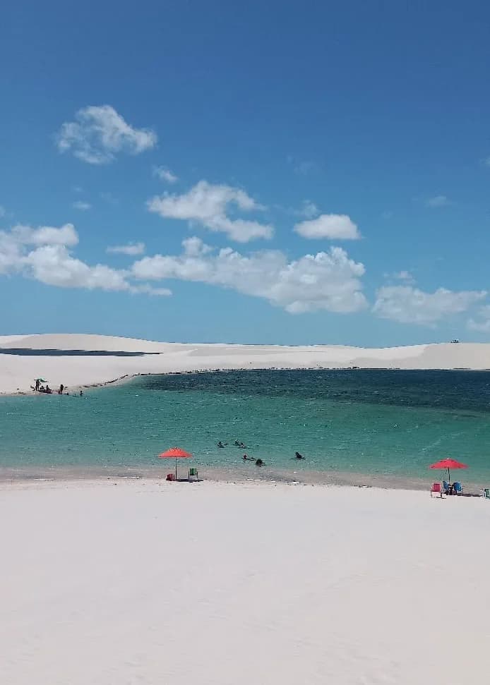 Banhistas na Lagoa da Andorinha entre dunas brancas nos Lençóis Maranhenses
