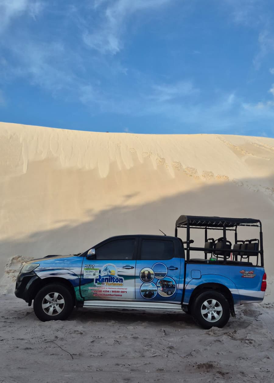 Hilux 4x4 azul da Renilton Turismo em frente a duna branca ao pôr do sol