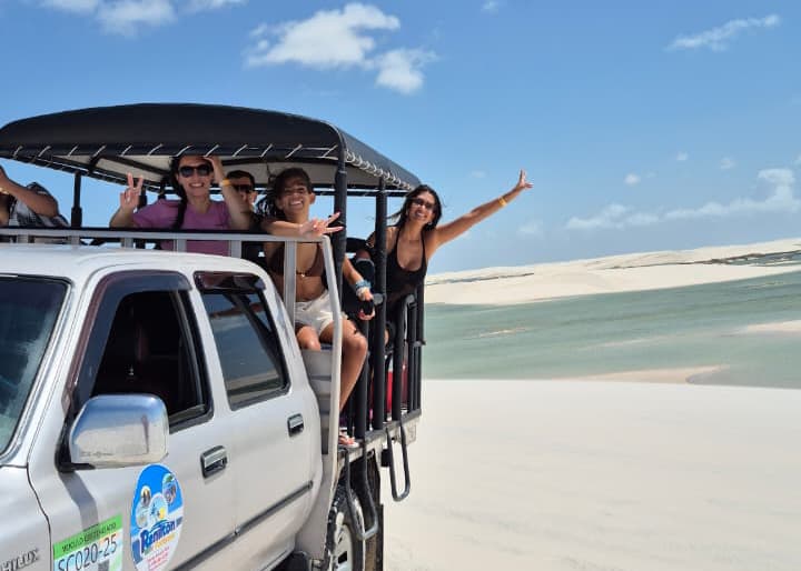 Turistas felizes comemorando na caçamba da 4x4 nos Lençóis Maranhenses