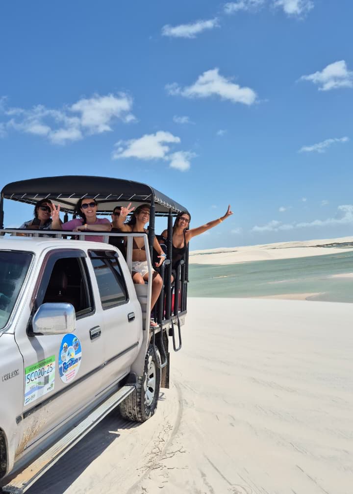 Turistas com braços erguidos comemorando passeio nos Lençóis Maranhenses
