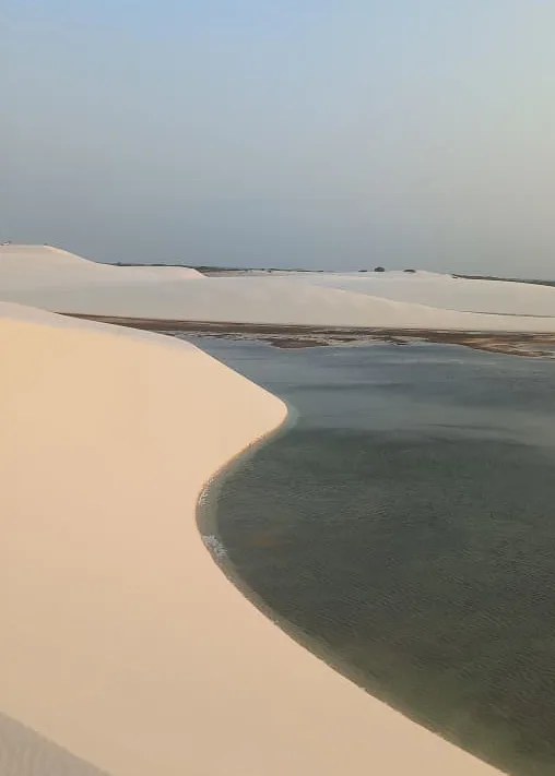 Lagoa em curvas entre dunas ao entardecer nos Lençóis Maranhenses