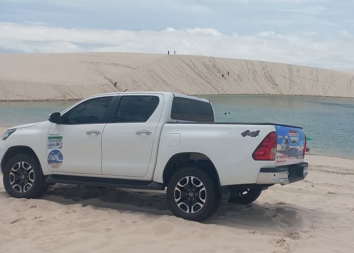 Hilux 4x4 da Renilton próxima a lagoa com turistas subindo duna